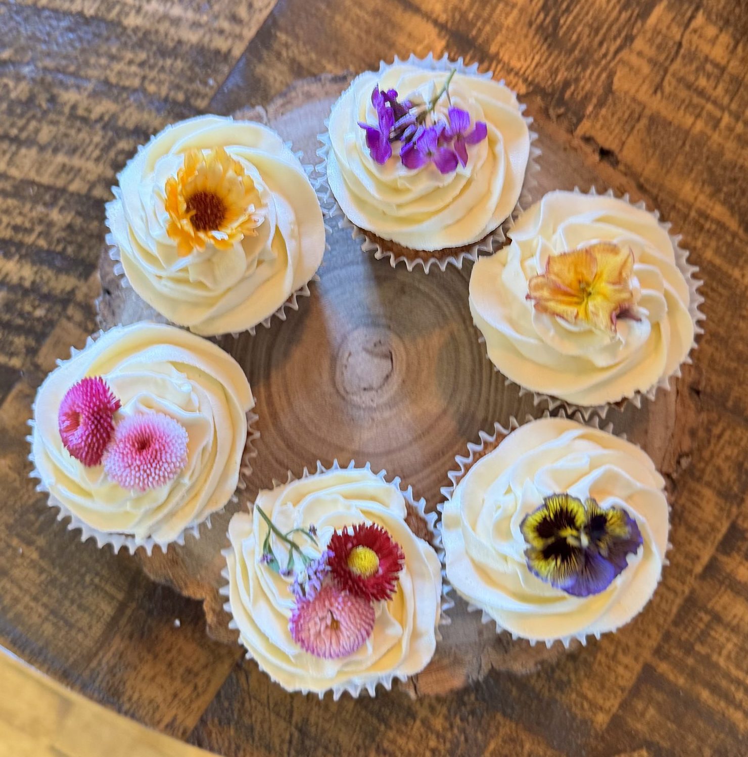 Bespoke wedding cupcakes featuring delicate edible flowers and professional artisan finishes, curated for a luxury dessert table installation in Fife, Scotland.