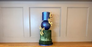 Architectural wedding cake installation featuring metallic blue sphere and forest green tiers for luxury Scottish industrial venues
