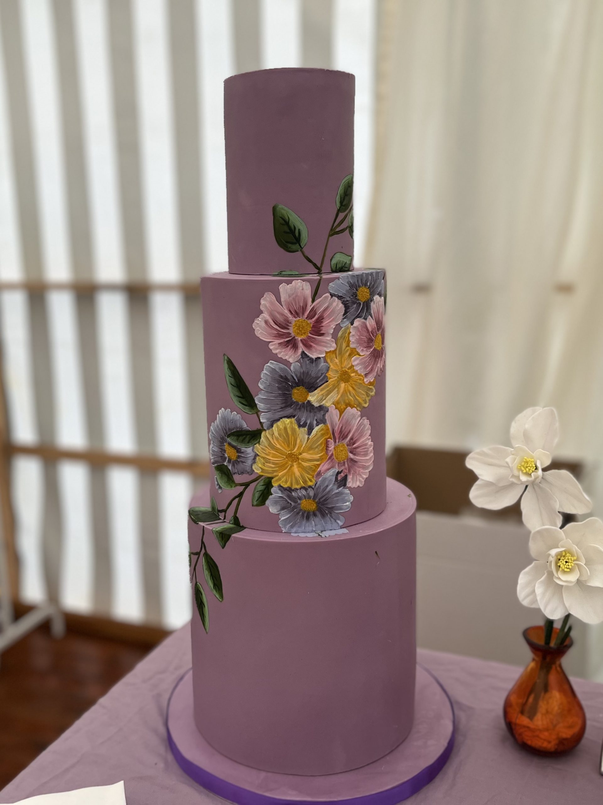 bespoke three-tier wedding cake in deep lilac with hand-painted botanical floral artistry, designed as a premium sculptural commission for a luxury estate wedding in the Scottish Borders.
