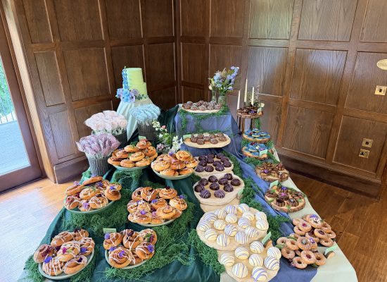 Luxury meadow garden wedding dessert table styling featuring bespoke artisan bakes, stacked natural stone, and moss by Crumbdidilyumptious in Scotland.