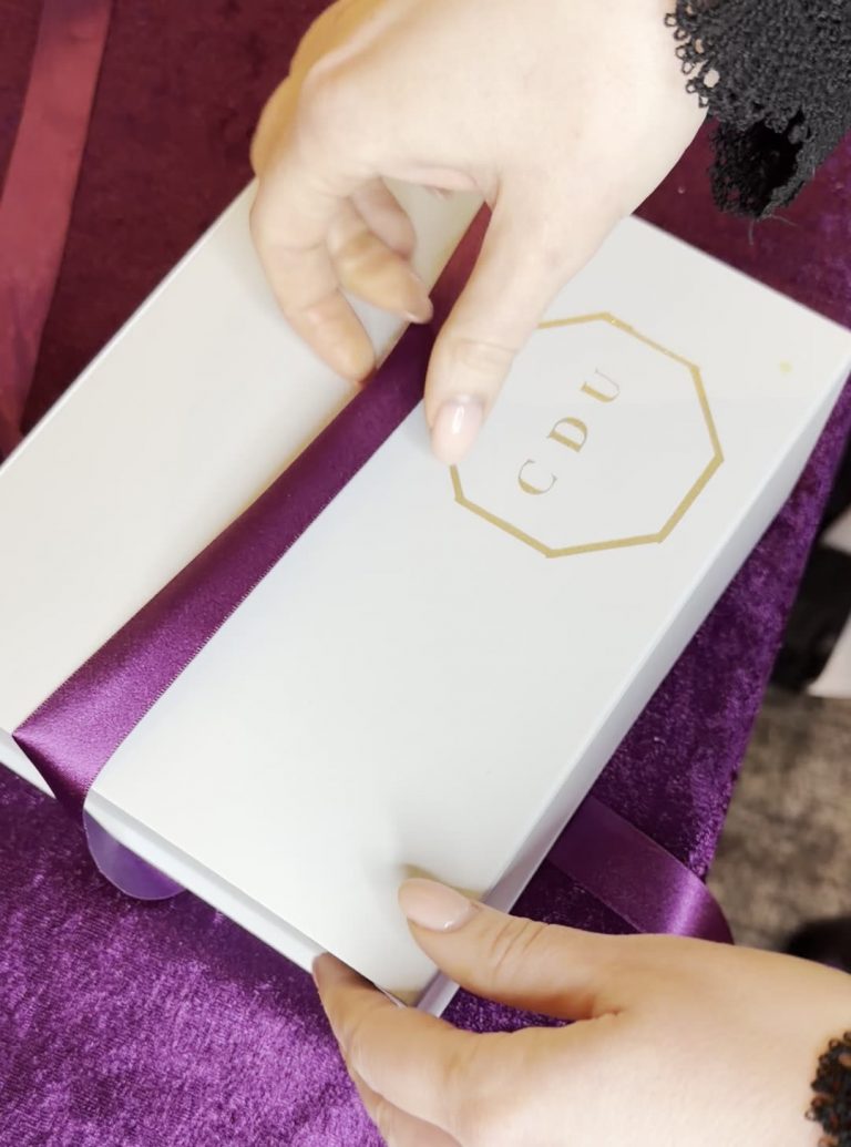 Pale blue wedding cake tasting box tied with deep purple satin ribbon and gold Crumbdidlyumptious CDU monogram Wedding Cake Fife FAQs