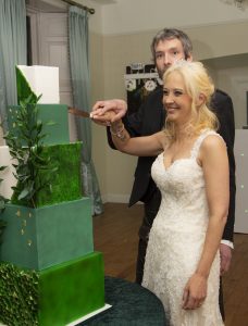 Bride and groom cutting their emerald green and gold wedding cake