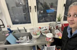 Kerrie Gourlay beside a sink piled with mixing bowls, spatulas and cake decorating equipment after working in the Crumbdidilyumptious cake studio