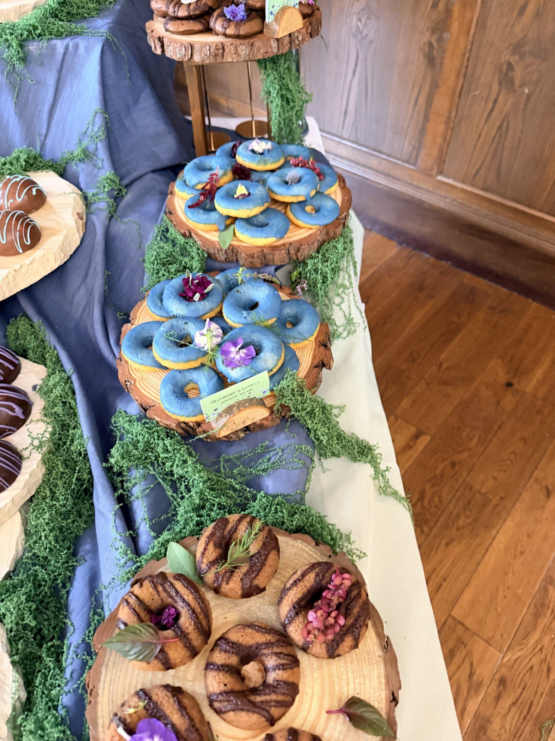 Luxury meadow garden wedding dessert table styling featuring bespoke artisan bakes, stacked natural stone, and moss by Crumbdidilyumptious in Scotland.